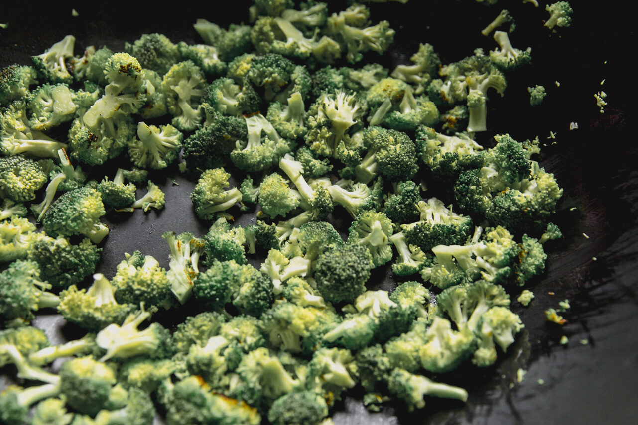 A wok with broccoli sauting in it.