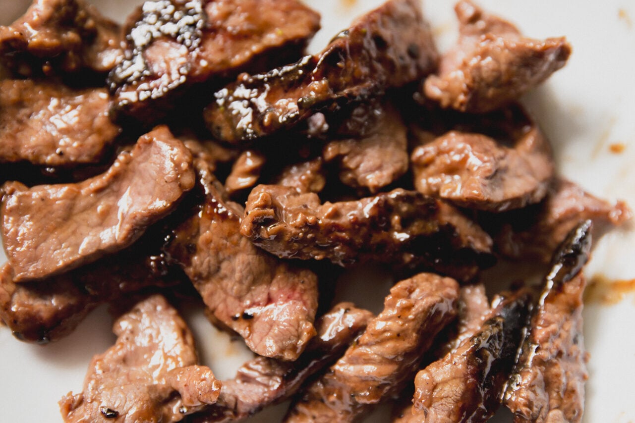 A white plate with cooked sirloin steak on it.