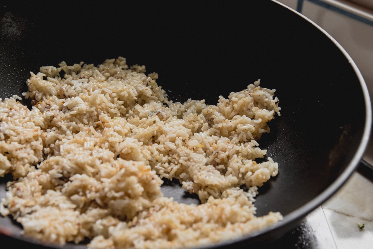 A wok filled with rice heating in it.