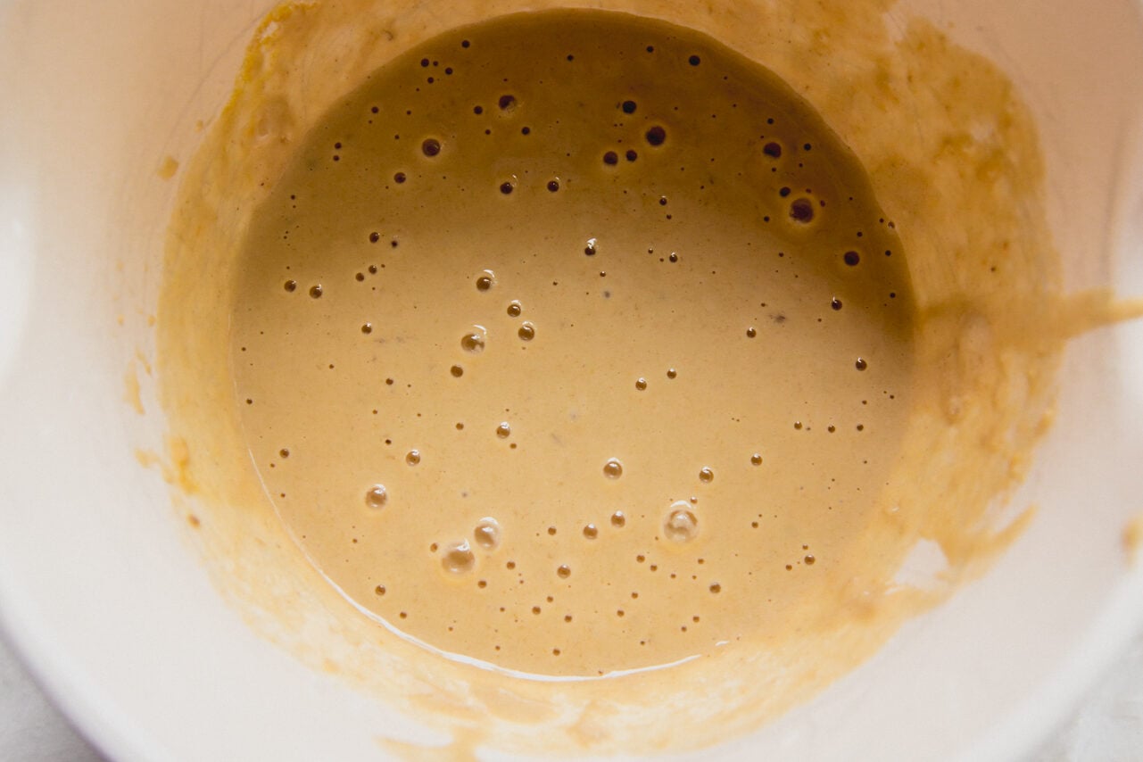 A white ceramic bowl with batter for berry protein breakfast cake in it.
