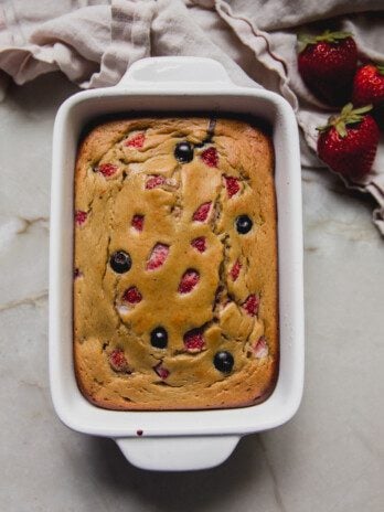 Berry protein breakfast cake in a small ceramic baking dish.