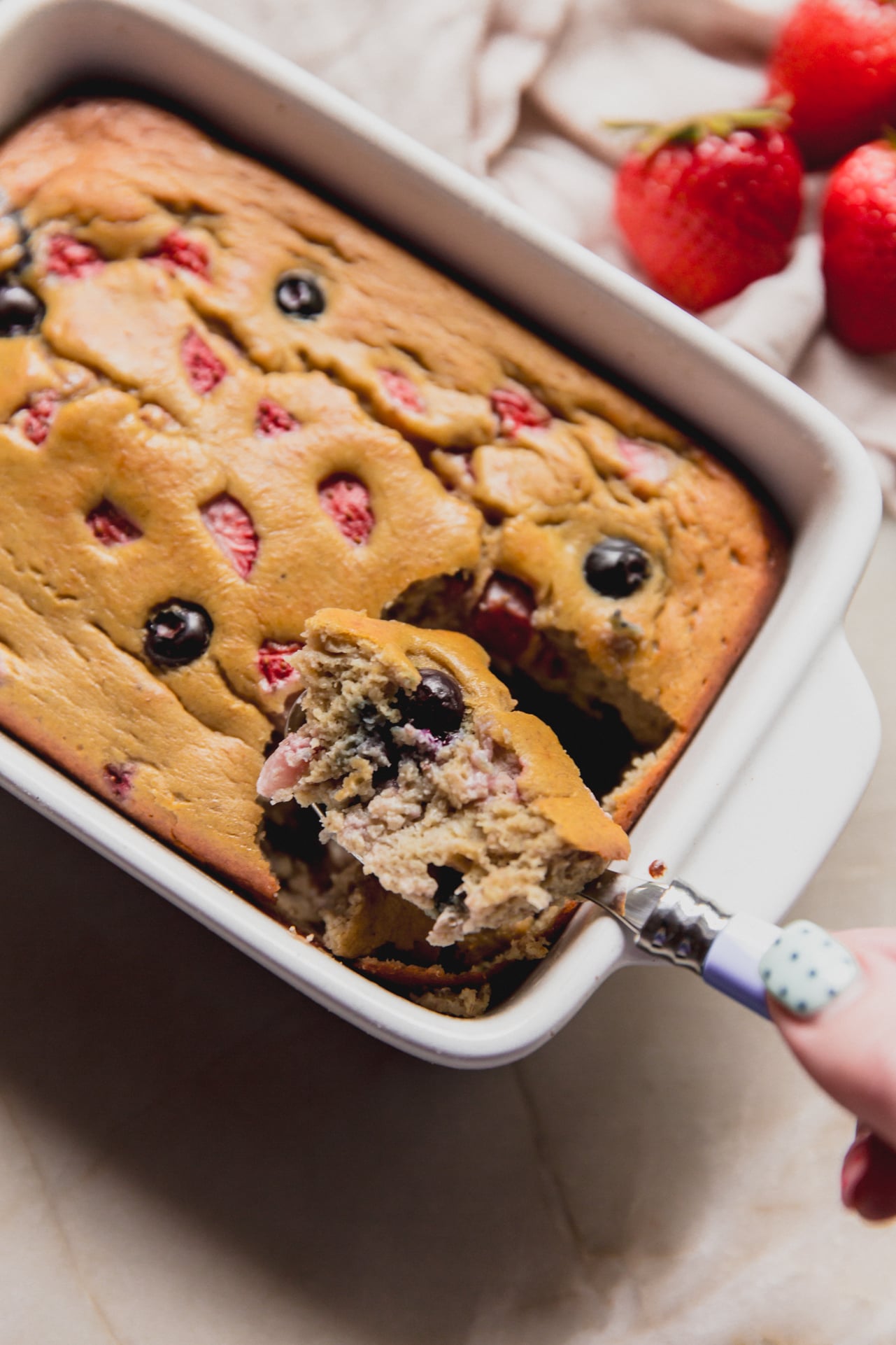 A spoon taking a scoop out of the berry protein breakfast cake.