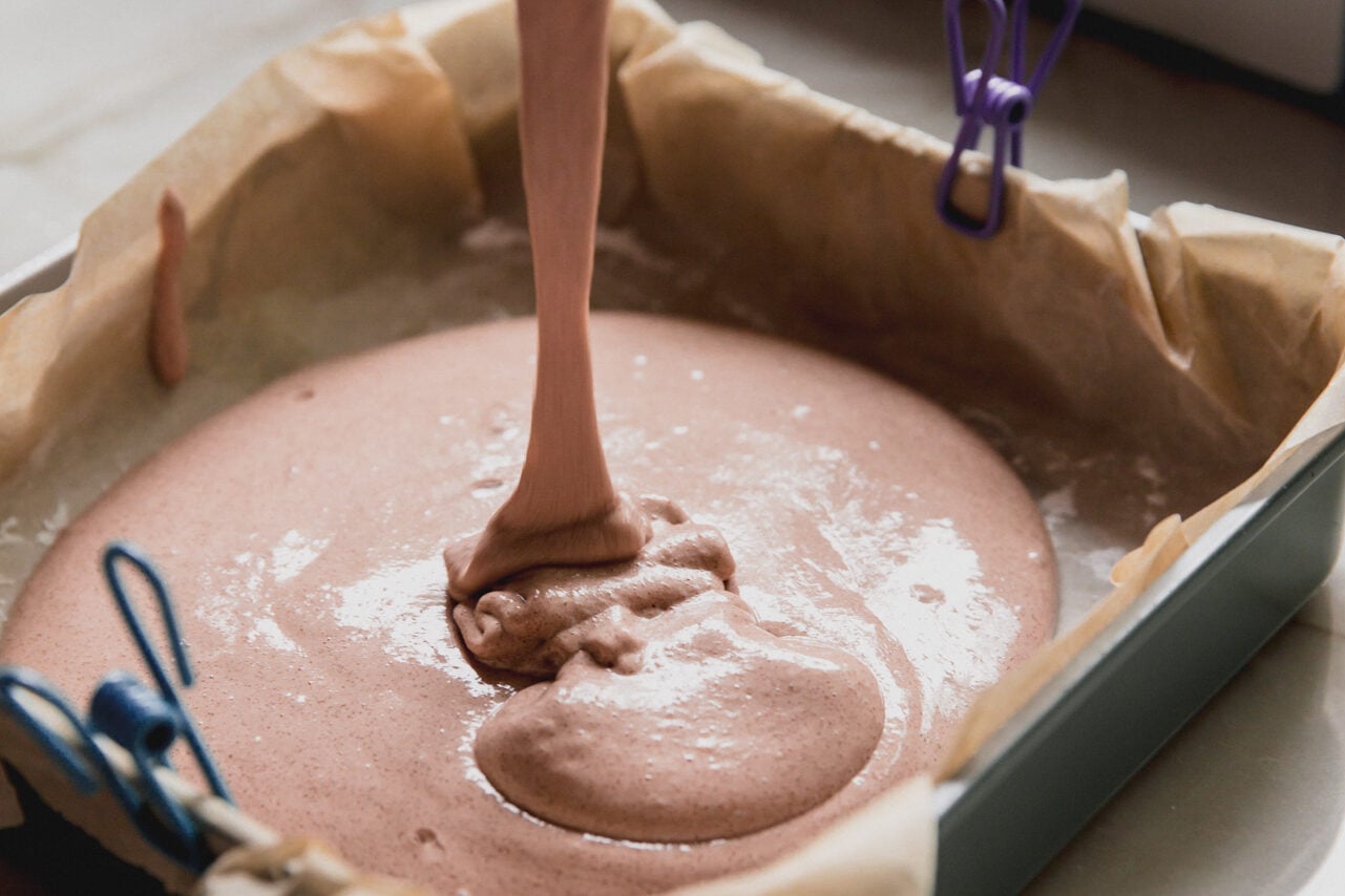 The marshmallow mixture being poured into a pan lined with parchment paper.