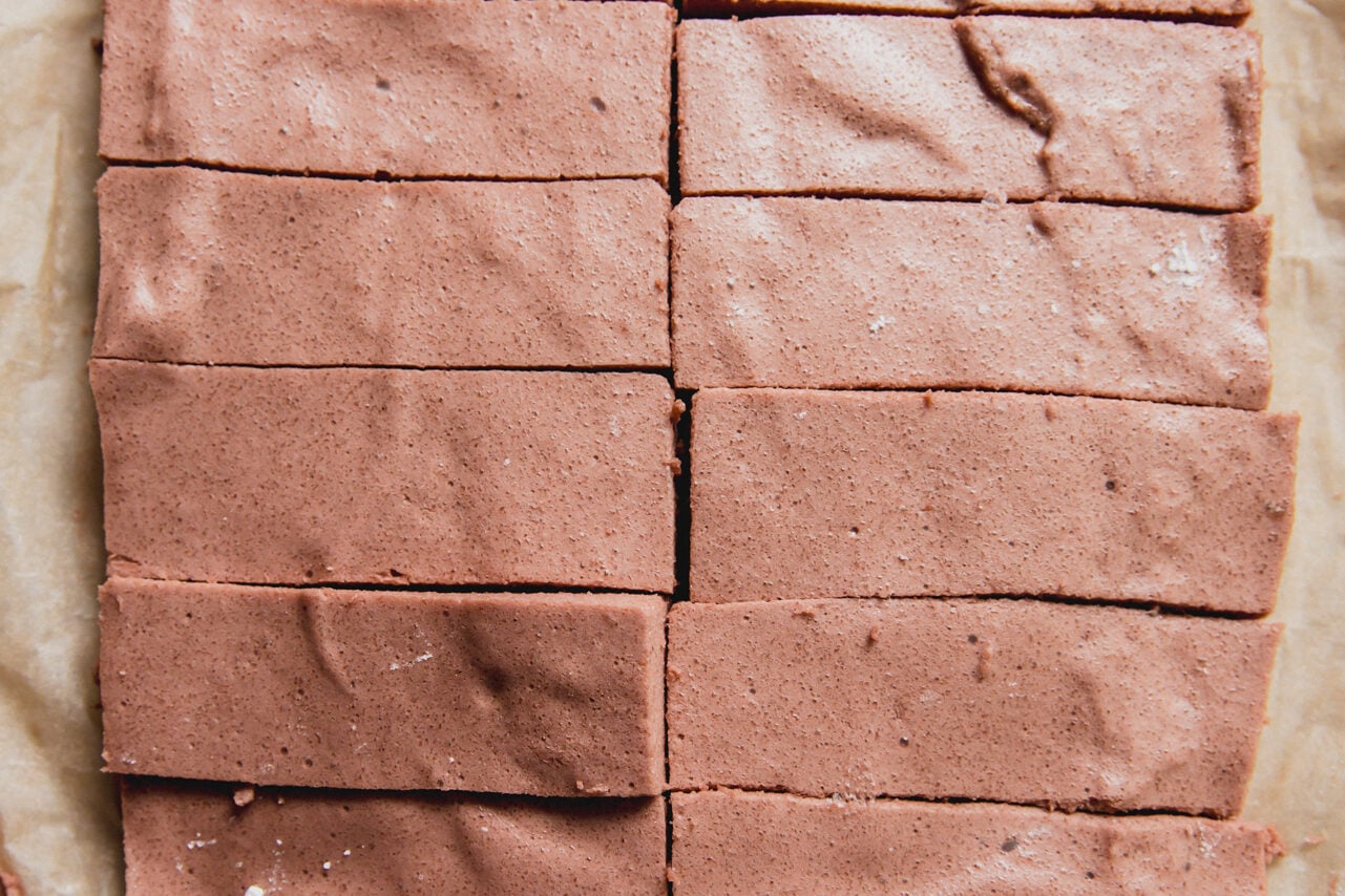 The marshmallows after setting in the fridge cut into 10 bars sitting on a piece of parchment paper.