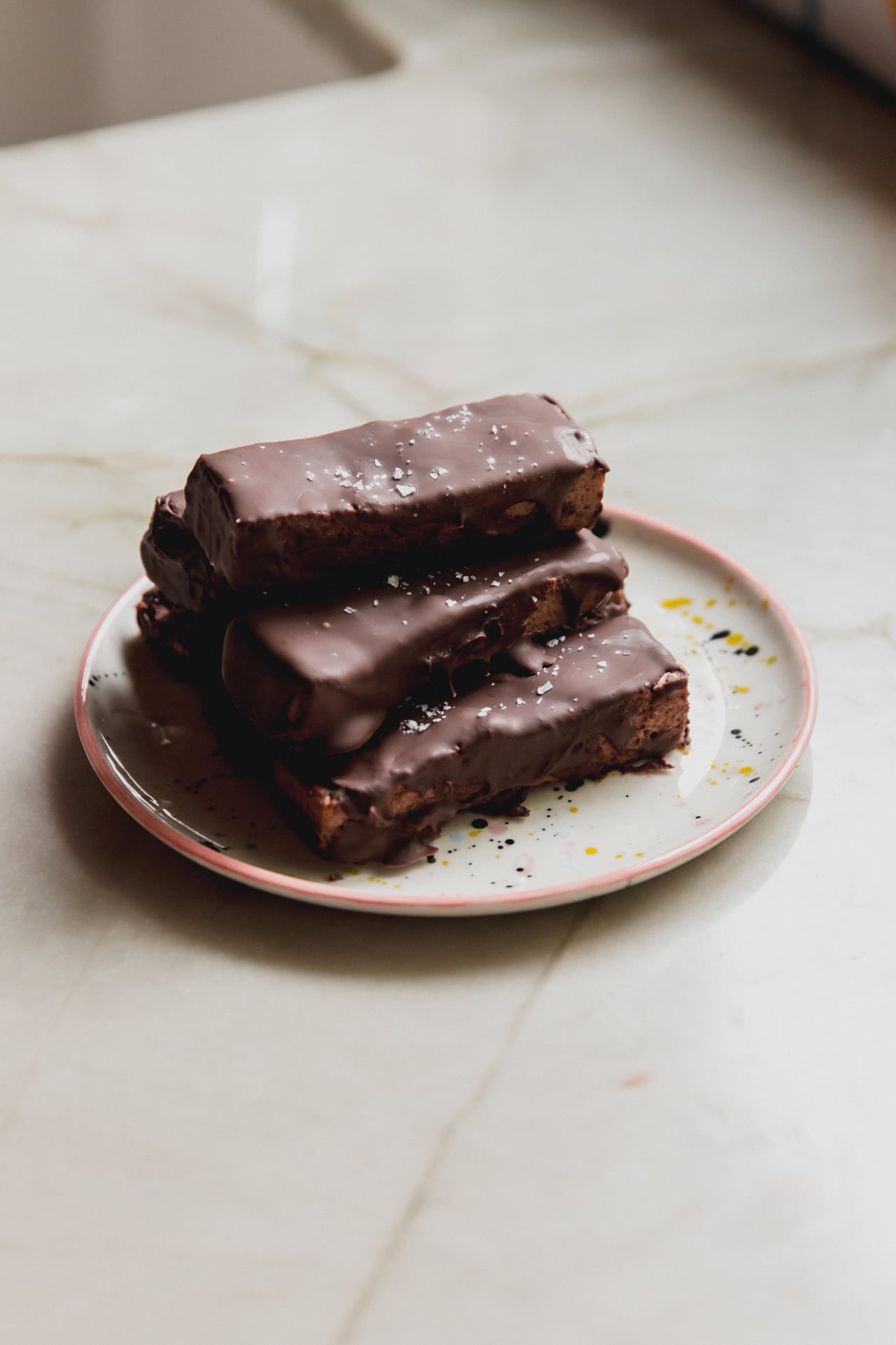 Brownie marshmallow protein bars stacked on top of each other on a plate. 