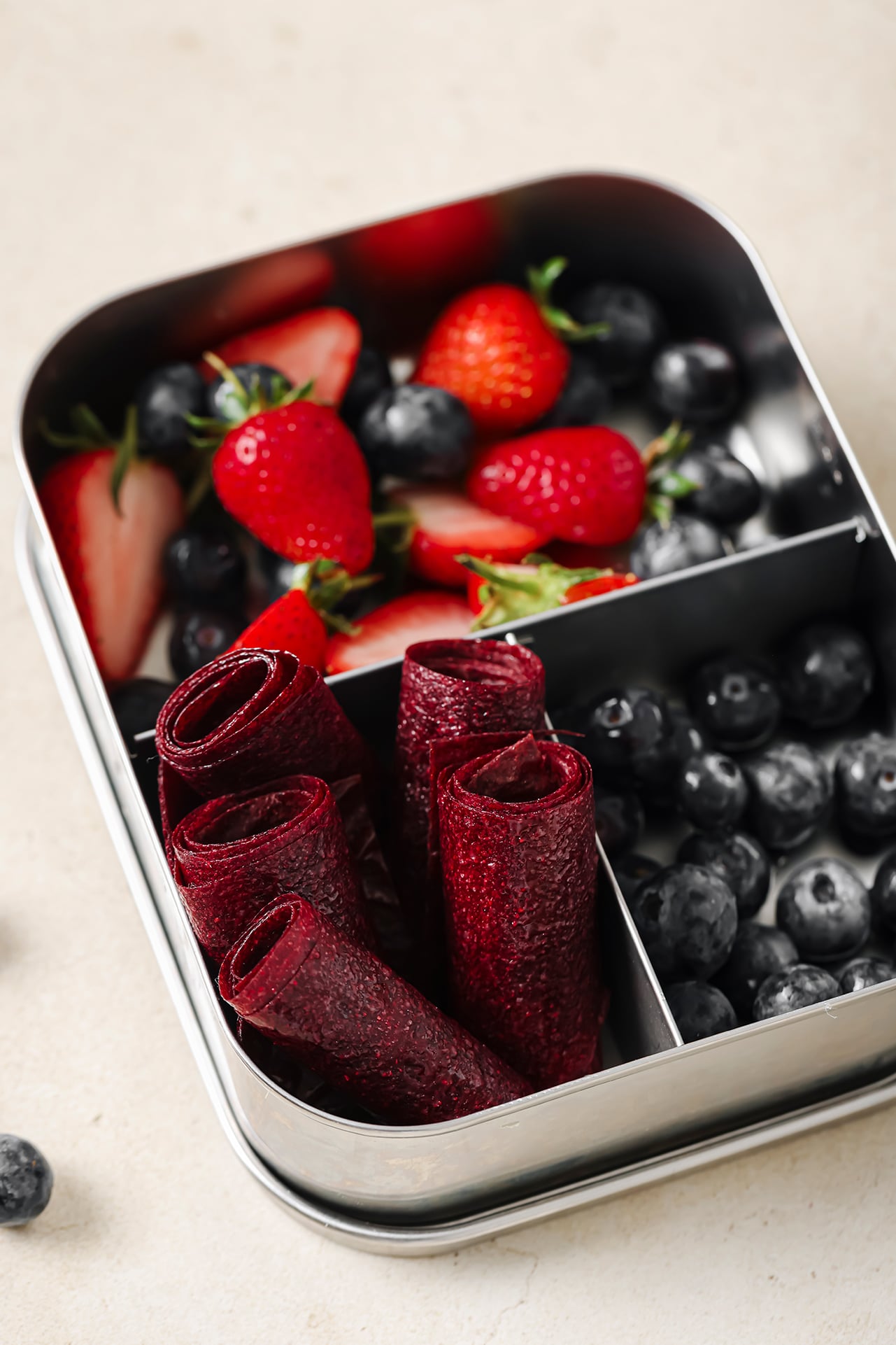 Fruit leather roll ups in lunch box with other fresh berries.