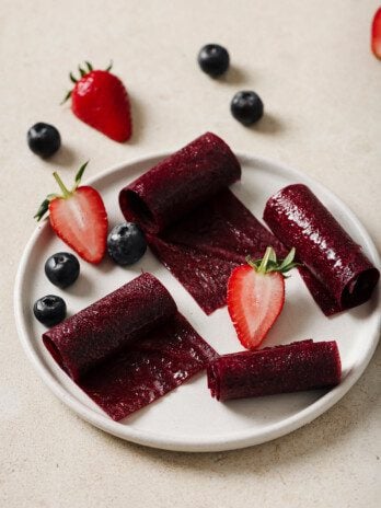 Fruit roll ups on a white plate with fresh berries.