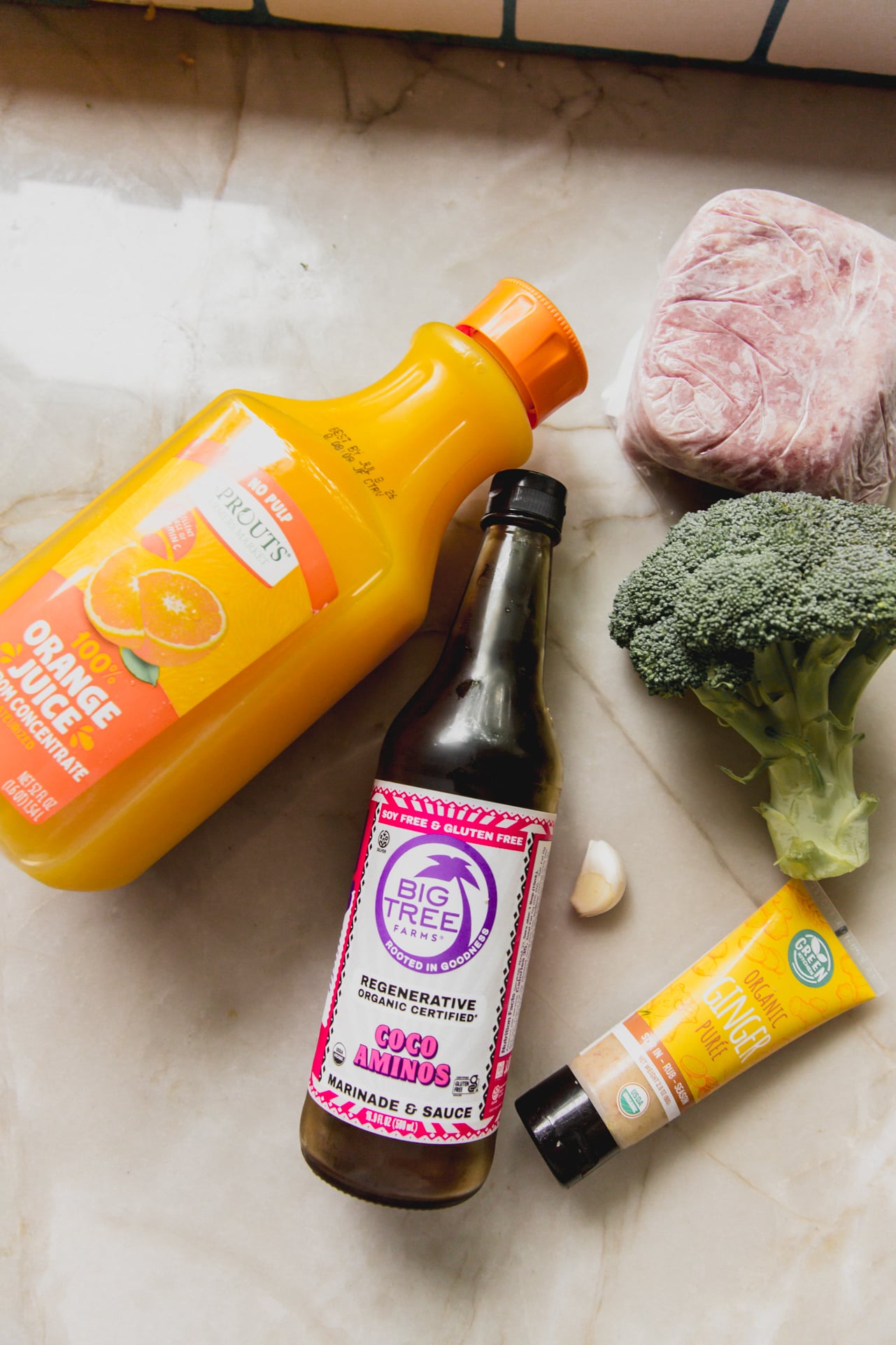 Orange ground chicken bowl ingredients on a marble counter top.