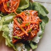 teriyaki salmon lettuce wrap with rice and topped off with shredded carrots.