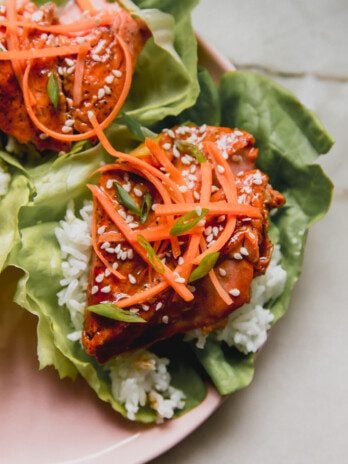 teriyaki salmon lettuce wrap with rice and topped off with shredded carrots.