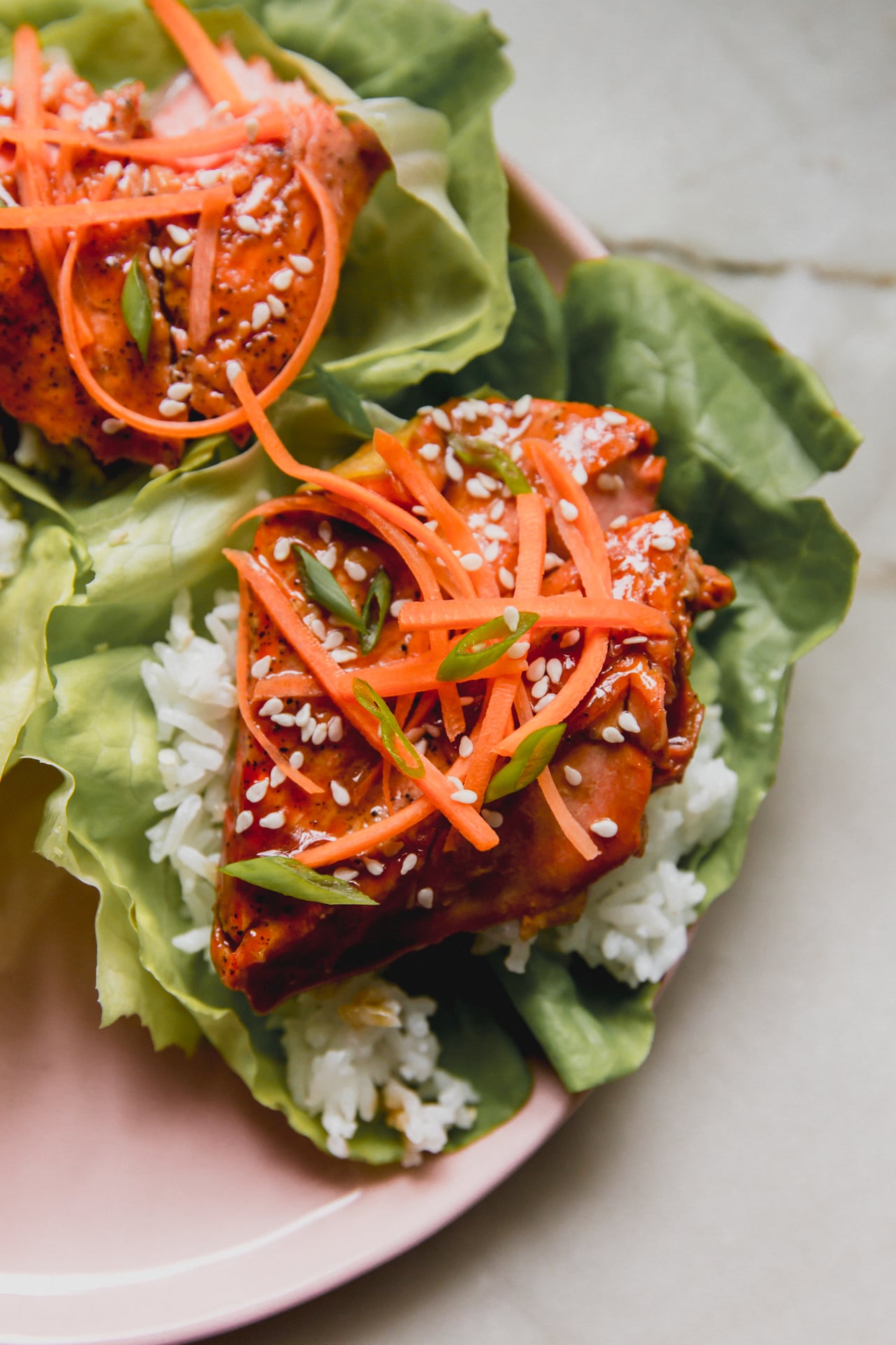 teriyaki salmon lettuce wrap with rice and topped off with shredded carrots.