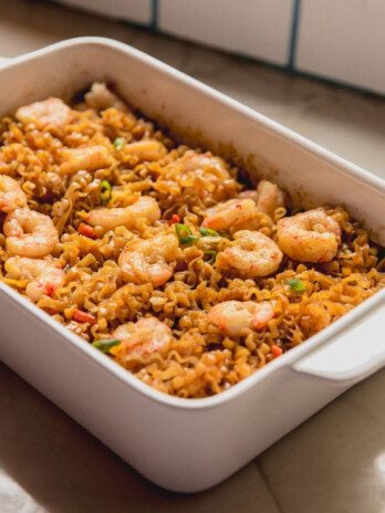 Cooked shrimp and ramen in a large white glass baking dish.