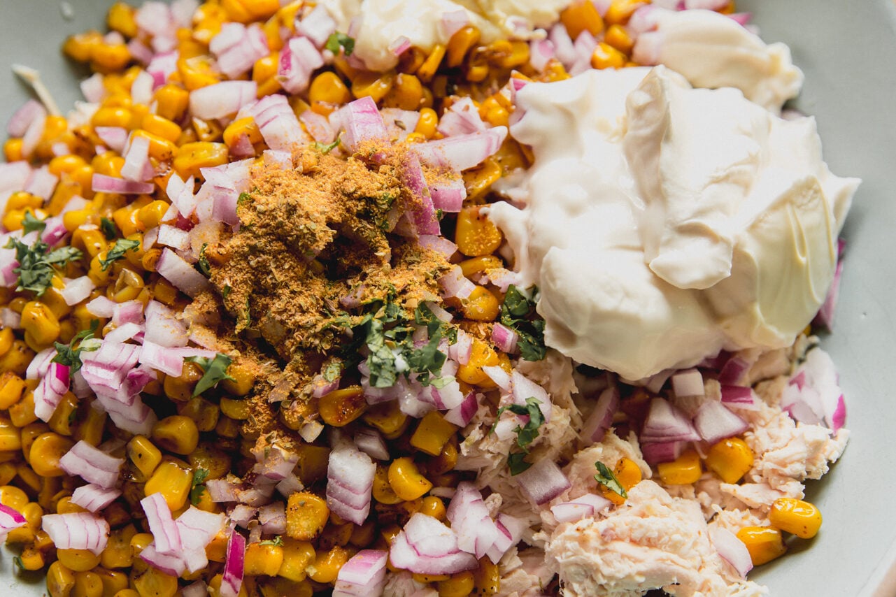 A bowl filled with all the ingredients to make street corn chicken salad before combining.