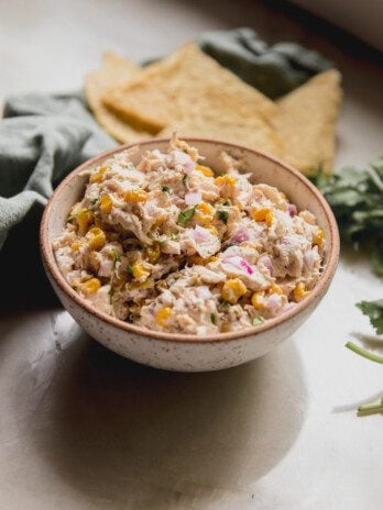 Street corn chicken salad in a bowl with tortilla chips in the background.