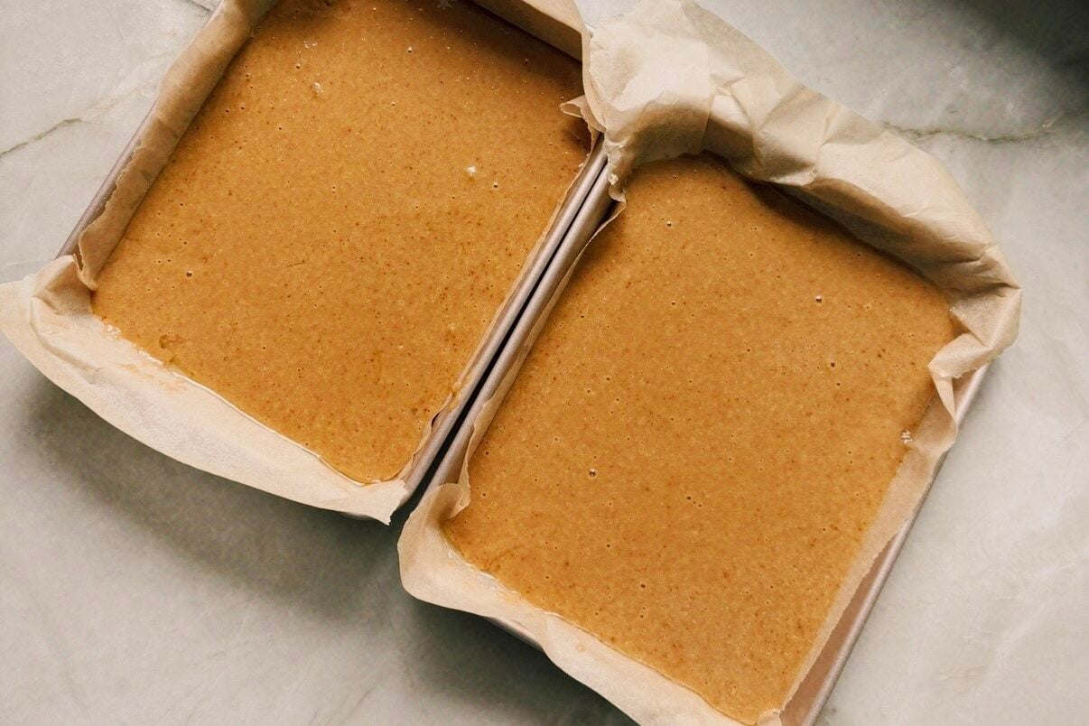 Two rectangular cake pans with cake batter.