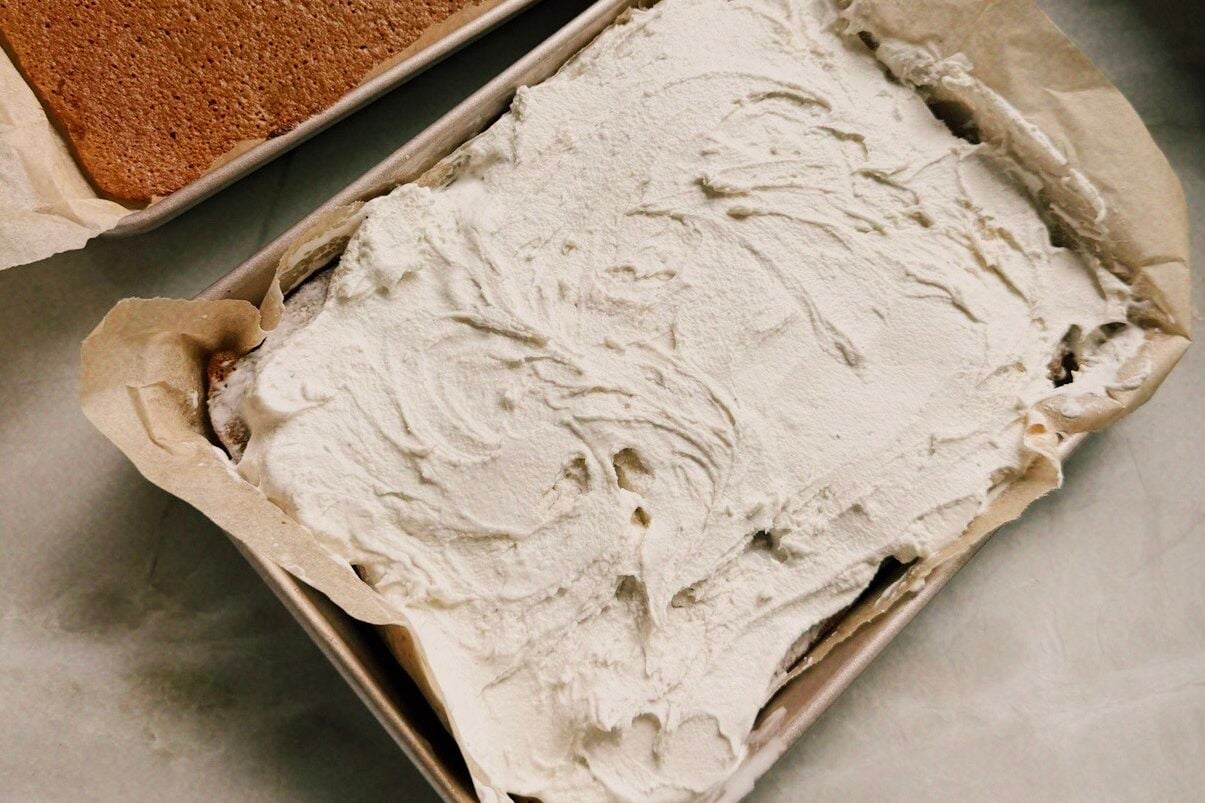 Two rectangular cake pans with cake, and one topped with ice cream.