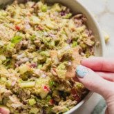 Avocado tuna salad in a bowl with a cracker dipping in.