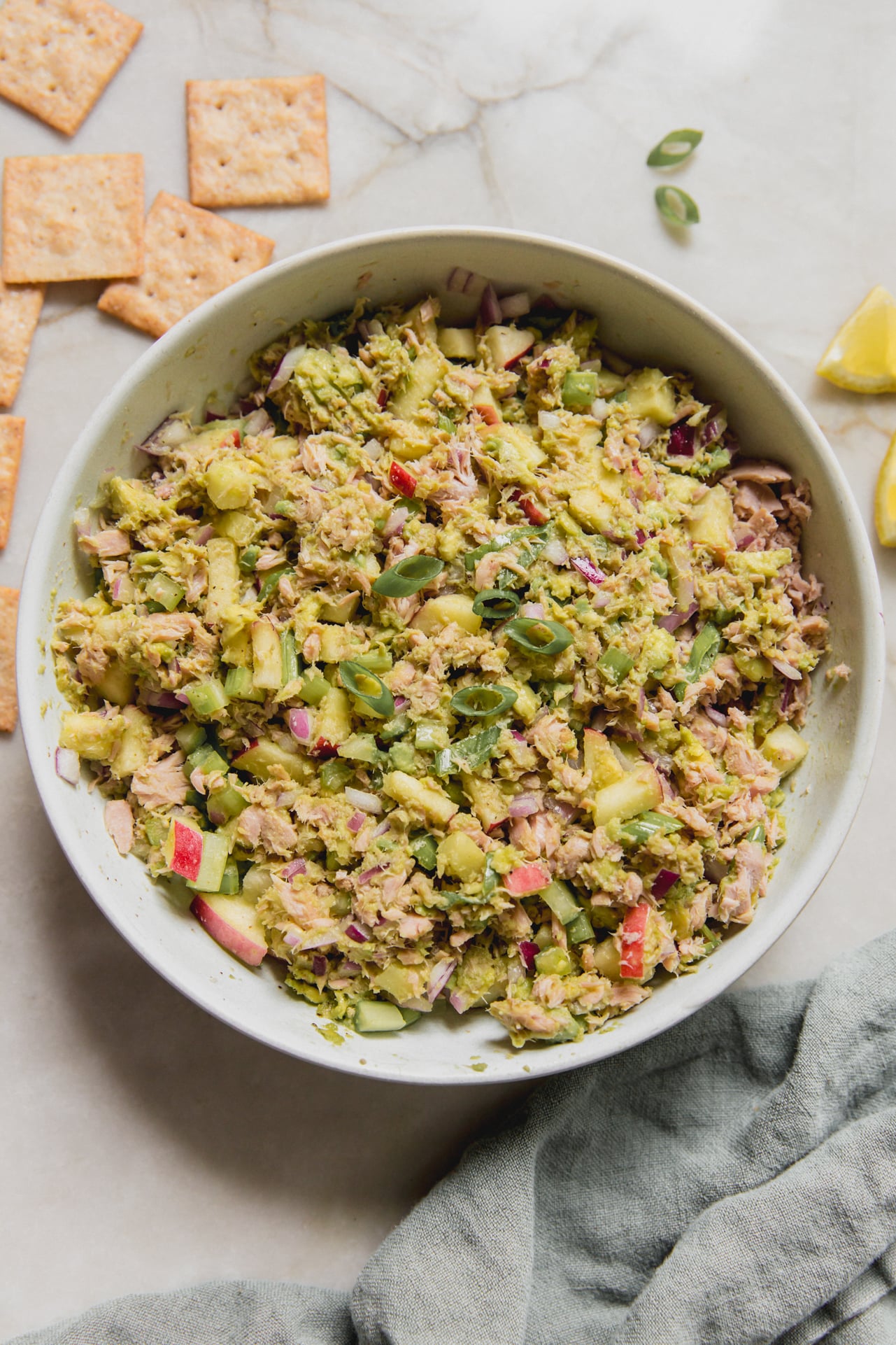 Avocado tuna salad in a bowl with crackers on the side.