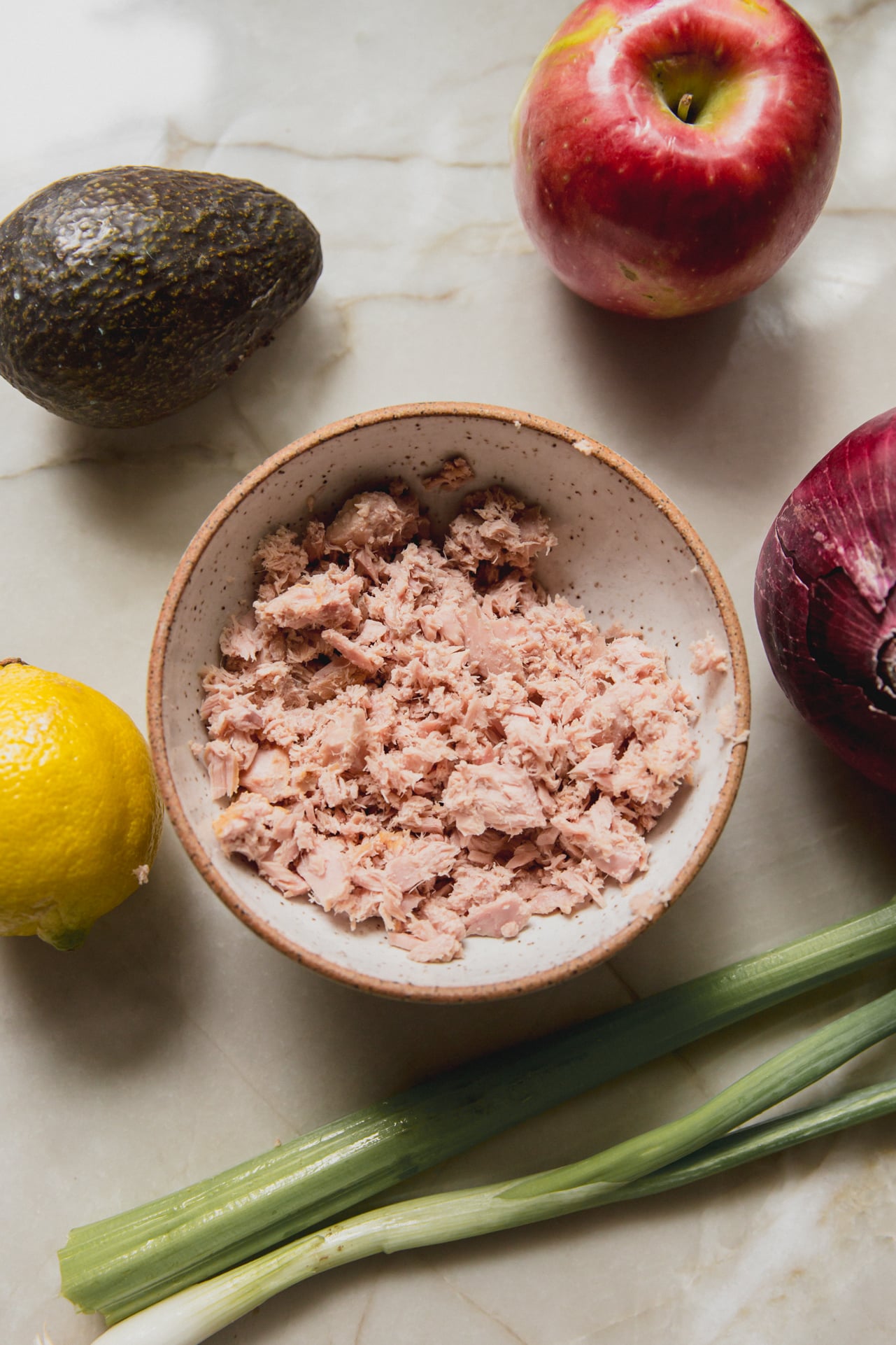 Avocado tuna salad ingredients on a marble counter.