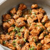 Gluten free chinese lemon chicken in a pan topped with green onion and lemon zest