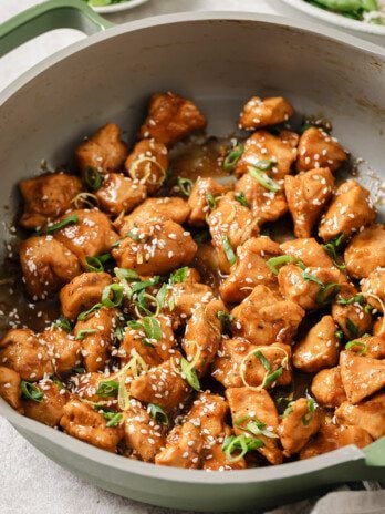 Gluten free chinese lemon chicken in a pan topped with green onion and lemon zest