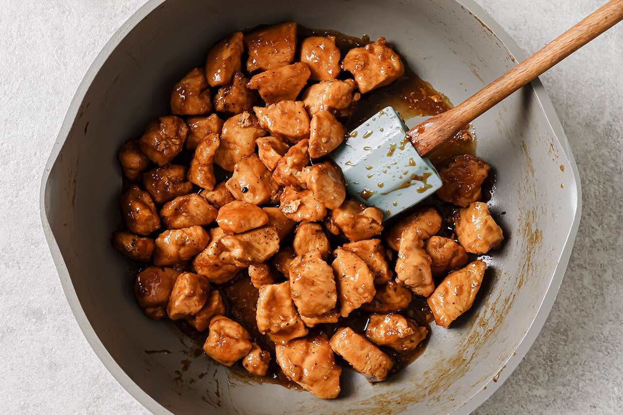 Cooked cubed lemon chicken in a pan coated in lemon sauce