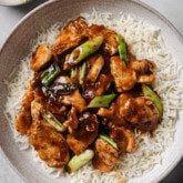 Gluten free mongolian chicken with green onions on a bed on white rice.