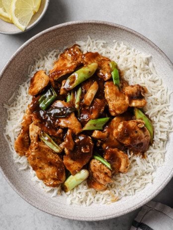 Gluten free mongolian chicken with green onions on a bed on white rice.