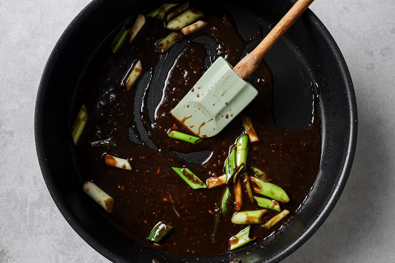 Green onion and mongolian sauce cooking in a pan.