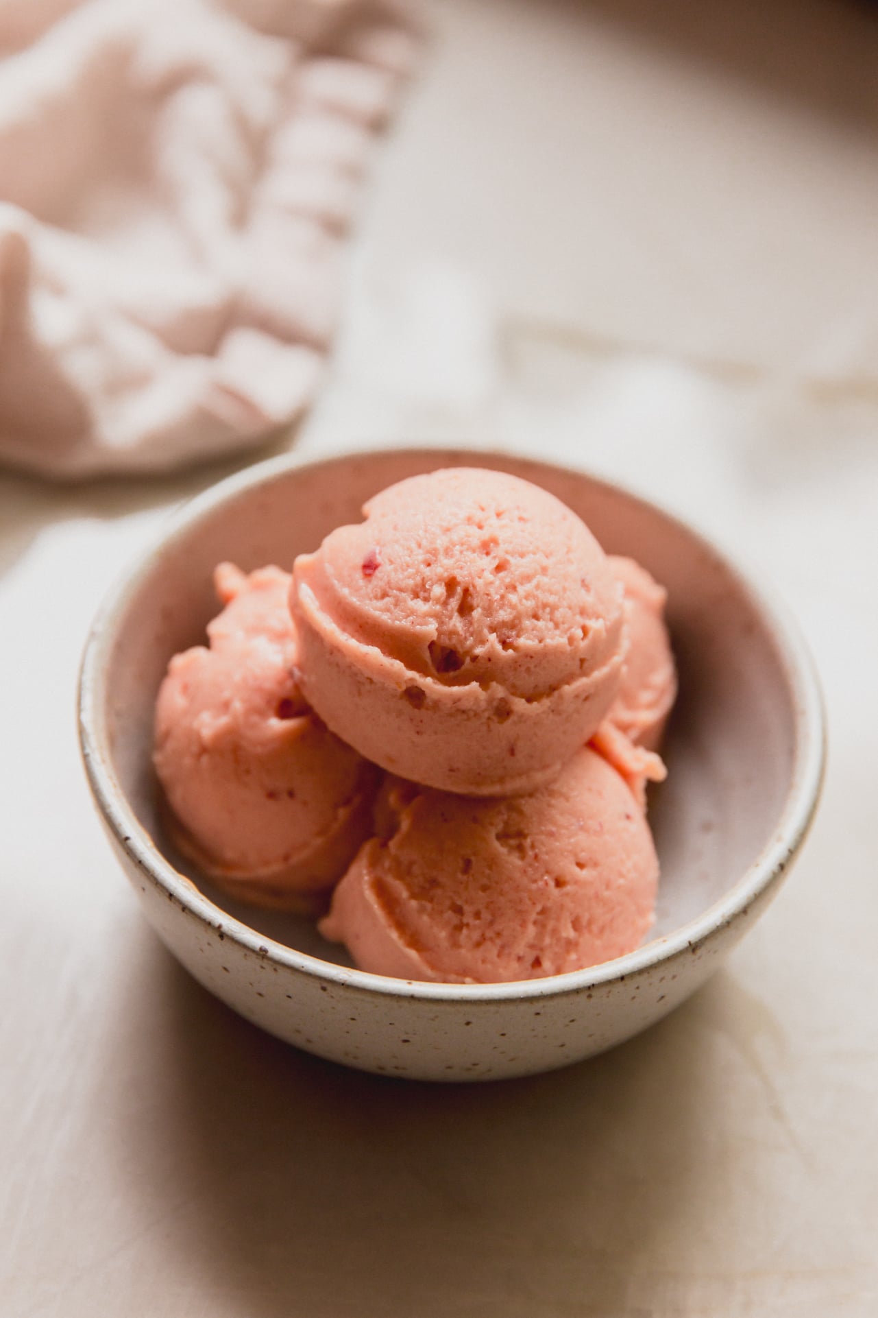 Three scoops of peach sorbet in a small bowl.