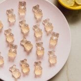 Pickle juice gummy bears on a plate with a bowl of pickles on the side.