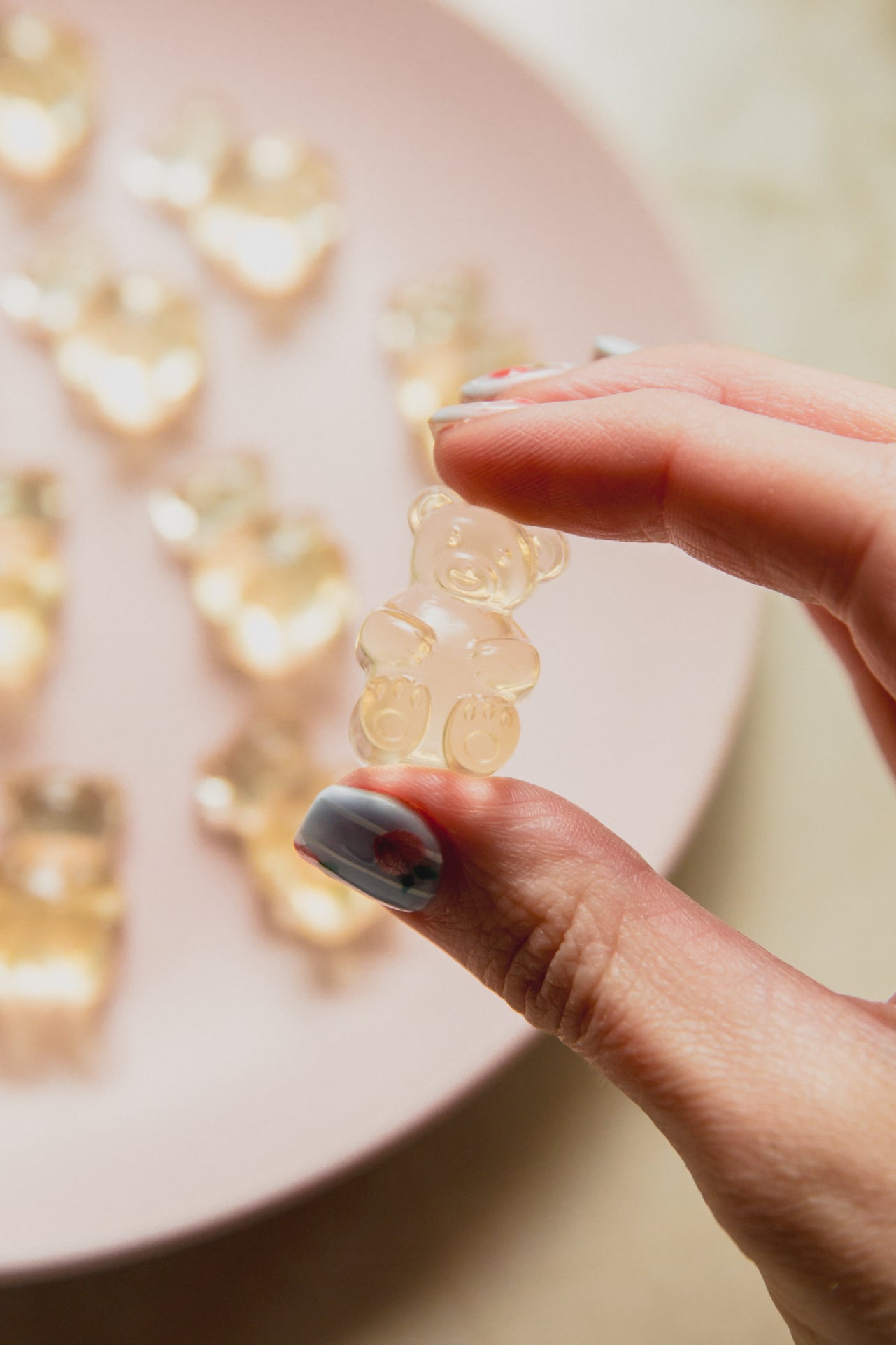 A hand holding a pickle gummy above a plate of pickle gummies.