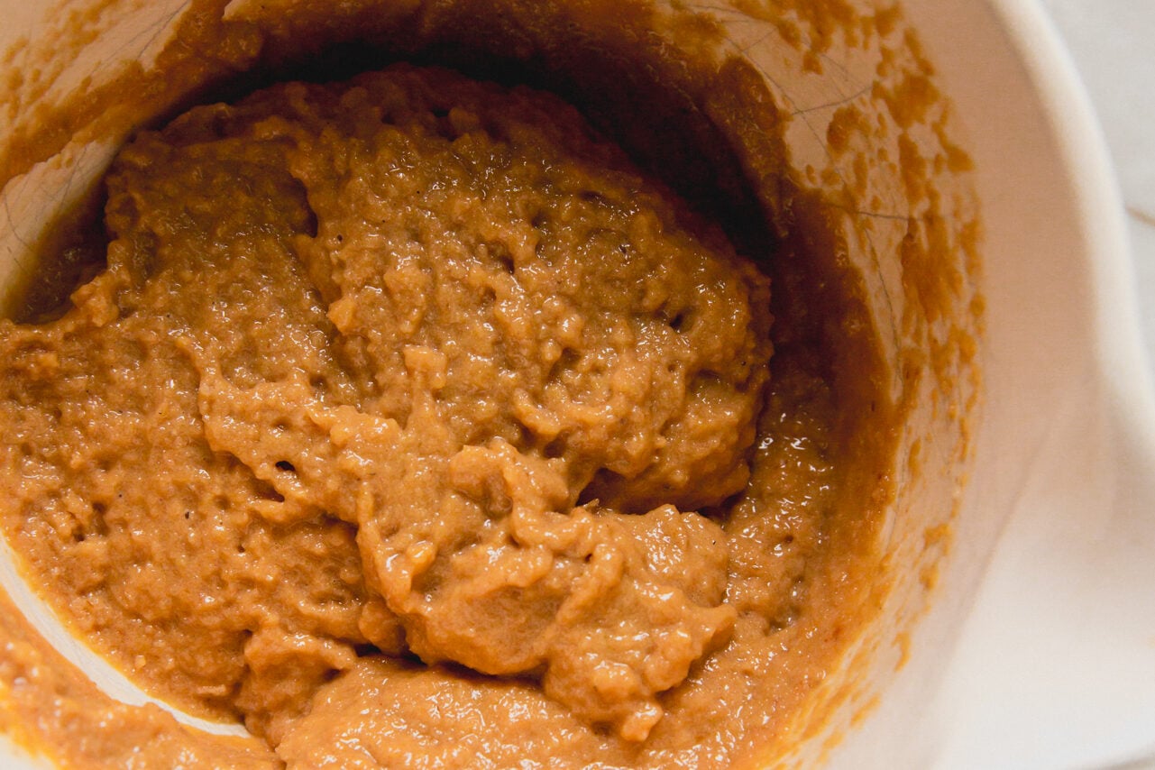 A white ceramic bowl filled with batter to make high protein muffins.