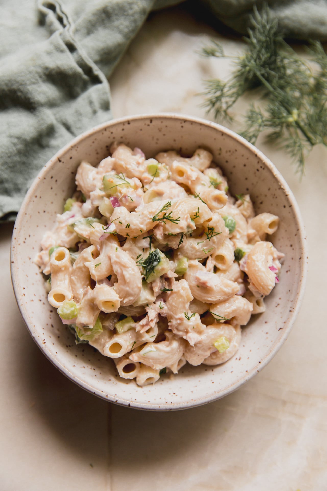 Tuna pasta salad in a bowl, topped with fresh dill