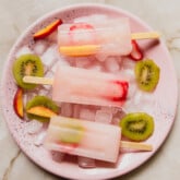 Three ginger and fruit popsicles on a pink plate.