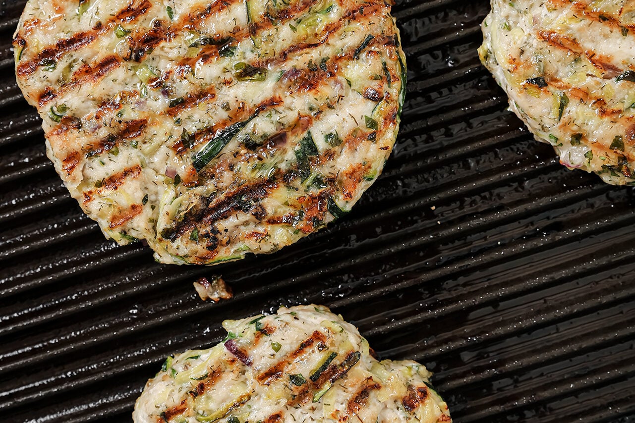 A grill pan with Greek chicken burgers on it after cooking.