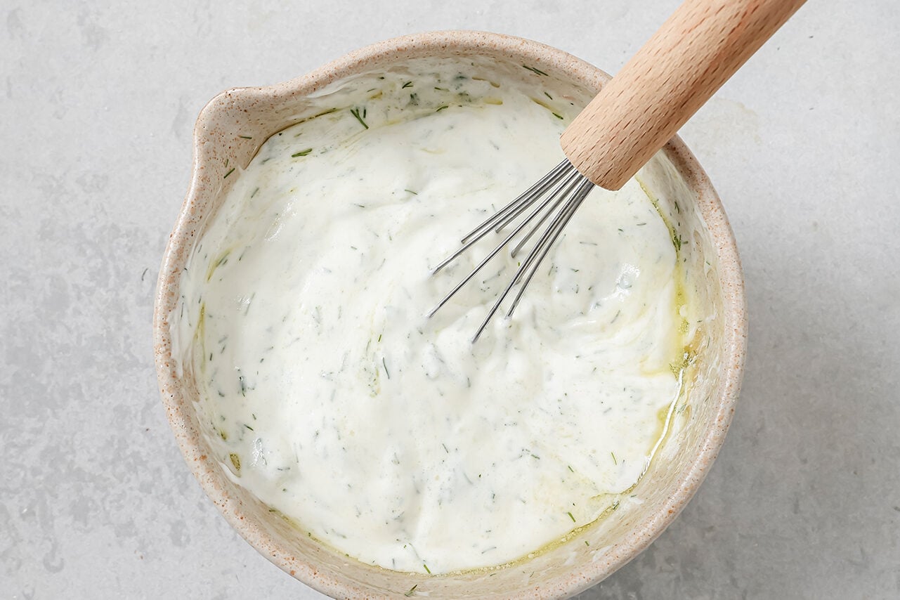 A bowl with all the ingredients for tzatziki sauce mixed together.