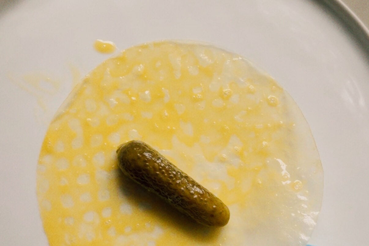 A pickle in the center of rice paper on a plate