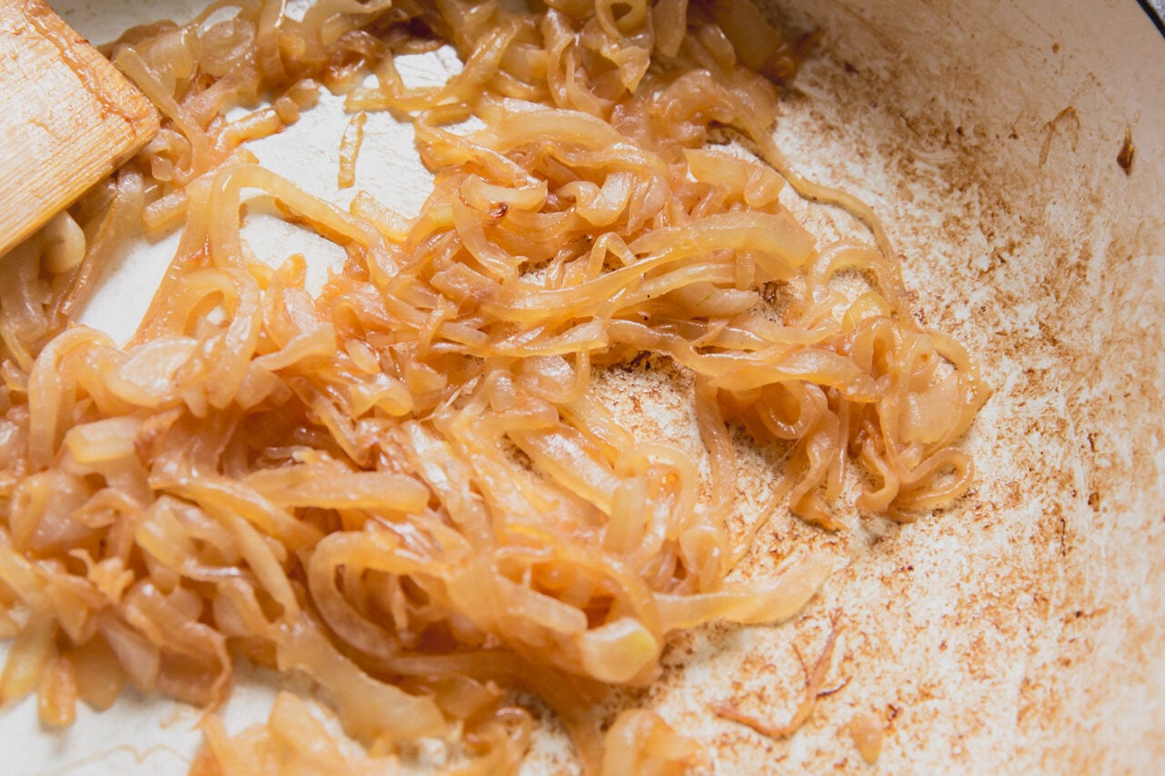 A pan with onions after caramelizing with a wooden spatula.