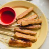 Pancake sausage sticks on a yellow enamel plate with a side on maple syrup in a bowl
