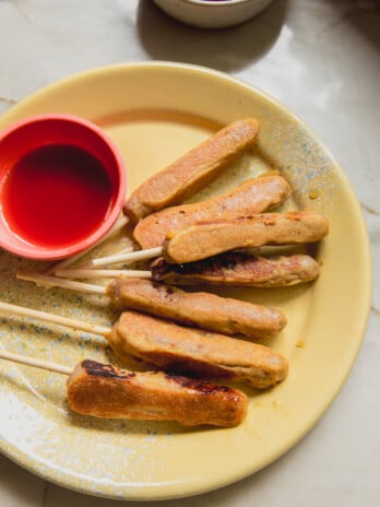 Pancake sausage sticks on a yellow enamel plate with a side on maple syrup in a bowl