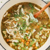 Chickpea chicken soup topped with chopped parsley in a white dutch oven.