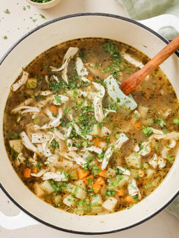 Chickpea chicken soup topped with chopped parsley in a white dutch oven.